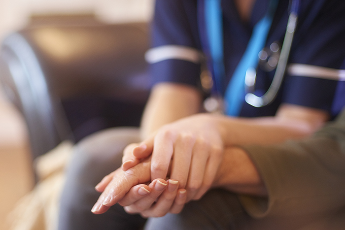 A female nurse consoles a senior patient at home